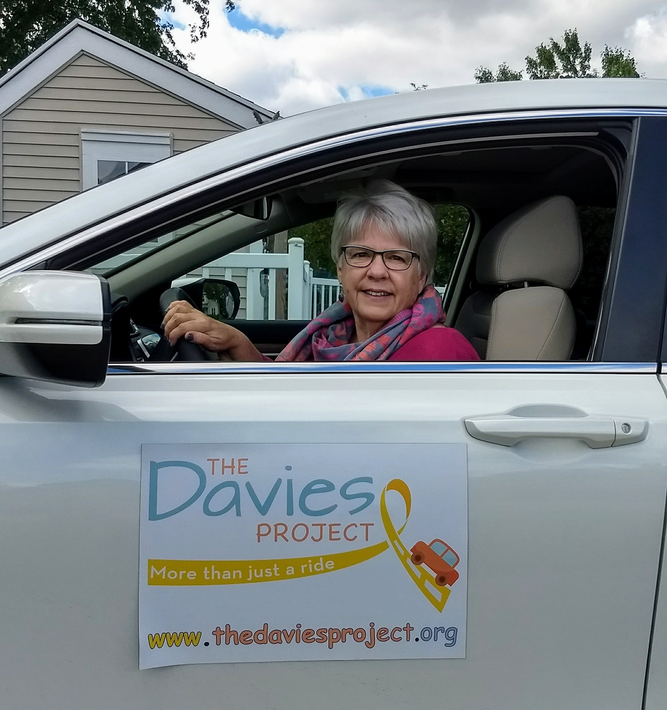 Driver in car with The Davies Project logo on car door